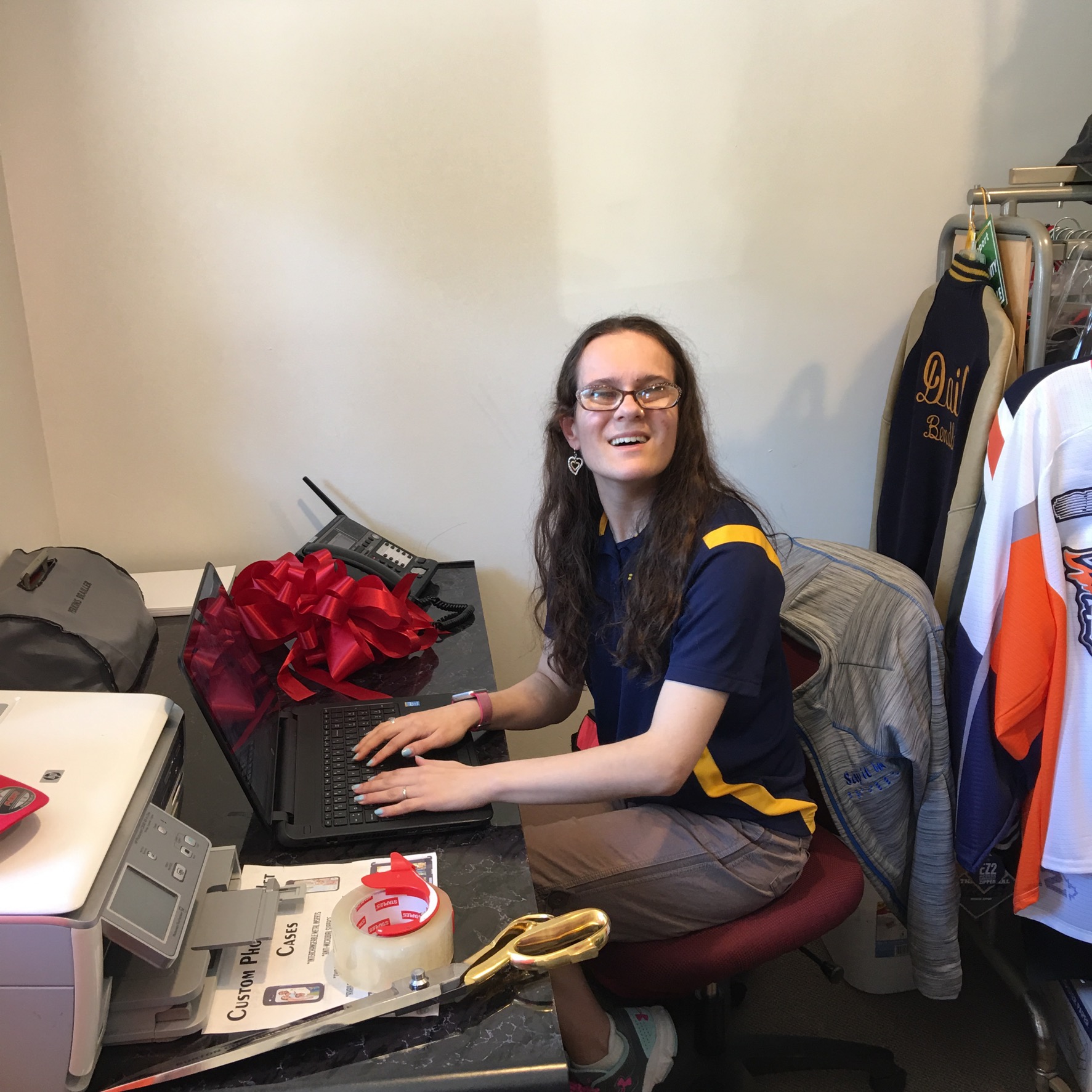 the webmaster is sitting at her desk, typing on her computer & smiling.